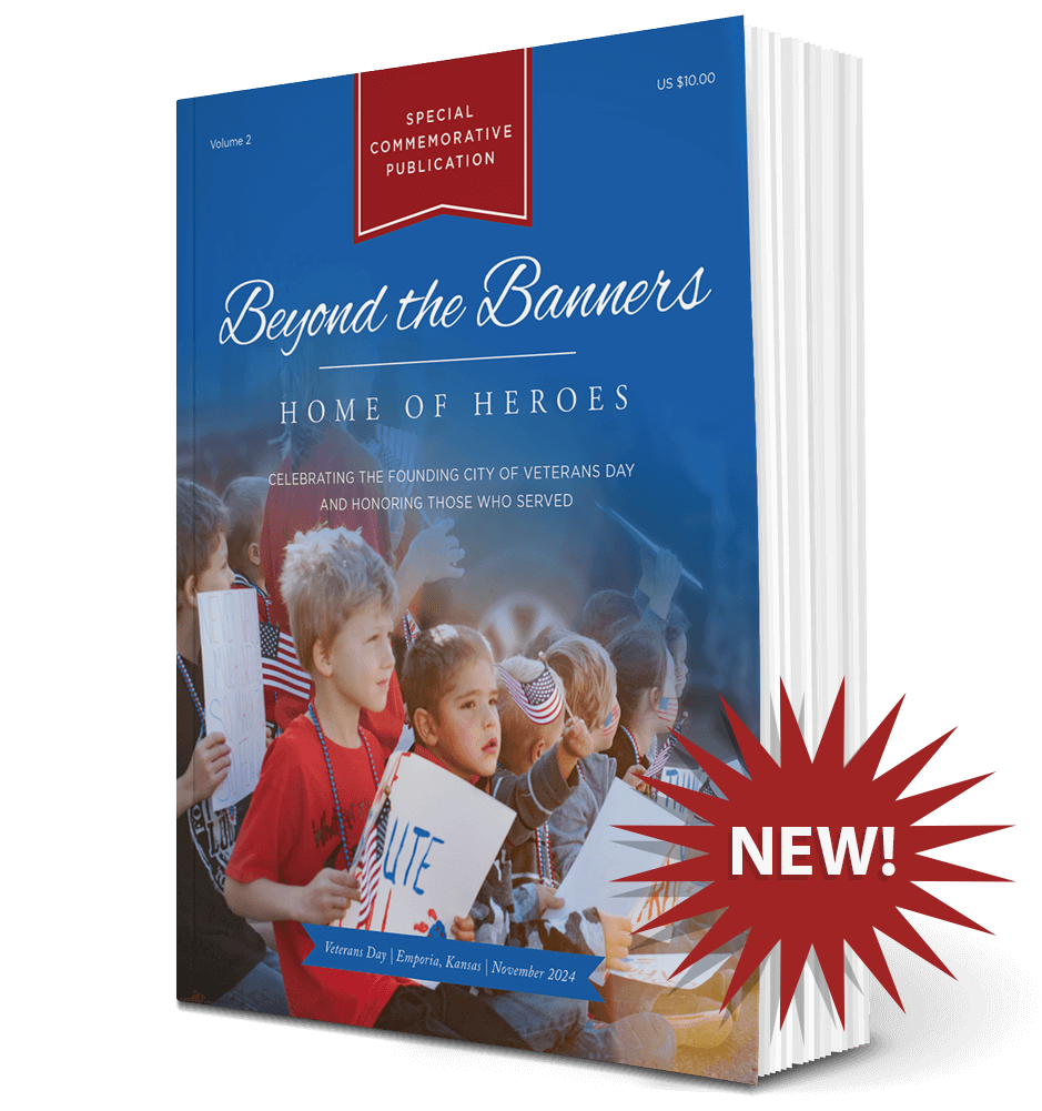 Volume 2 softcover of Beyond the Banners: Home of Heroes Volume 2. Over the image of the book is a sharp speech bubble with the word, "NEW!" The book's cover is blue, an image fading in on the bottom showing children holding little American flags and signs. Text on the top says, "Volume 1. Special Commemorative Publication. US $10.00." Text above the image of the children says, "Beyond the Banner: Home of Heroes, Celebrating the founding city of Veterans Day honoring those who served." Text on the bottom says, "Veterans Day | Emporia, Kansas | November 2014."